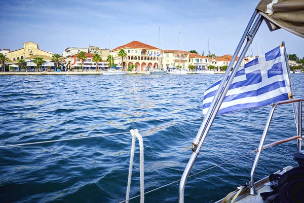 Bateau à voile avec un drapeau de la Grèce nage vers la ville. La charmante capitale de l'île de Paxos, la ville de Gaios est le port principal de l'île et est considéré comme l'un des plus beaux ports o — Photo