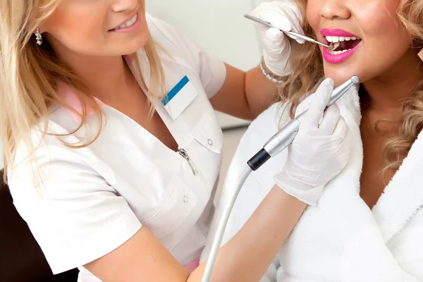 Kadın dişçi, dişçi muayenehanesinde metal parantez ile hastanın dişlerini kontrol ediyor. Tıp, dişçilik ve sağlık hizmetleri konsepti. Diş ekipmanları