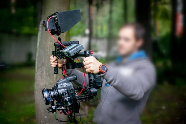 Imagem desfocada de filmagem ou produção de vídeo e equipe de equipe de filmagem com equipamento de câmera no local ao ar livre — Fotografia de Stock