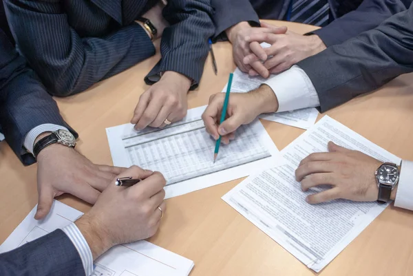 Bir grup işadamı şirketin planlarını ve stratejilerini hararetle tartışıyor ve yakın planlı bir şirkette masa başında oturup belgeleri imzalıyor.
