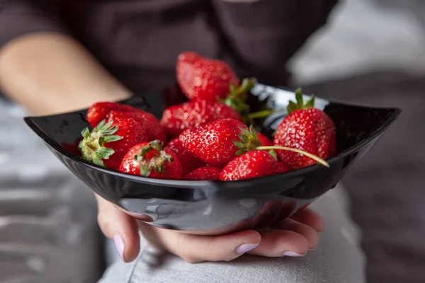 Fresh ripe strawberry in a black plate in the hands. Close-up photo — Stock Photo, Image