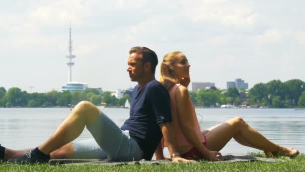 Week-end - un couple relaxant au bord de la rivière et écoutant de la musique sur écouteurs — Video