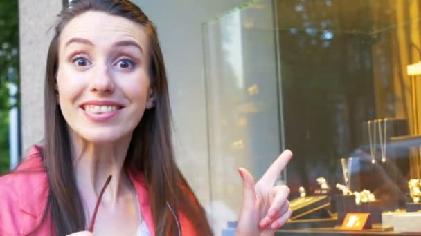 Young pretty woman is really excited about jewelry in a shop window — Stock Video