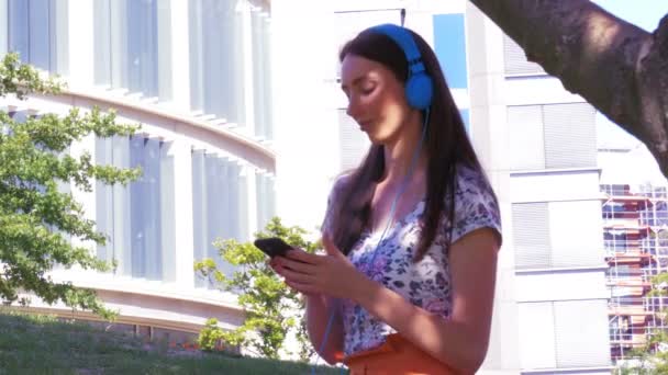 Estilo de vida moderno - una mujer alegre escucha música y se relaja en el parque de la ciudad durante el fin de semana — Vídeos de Stock