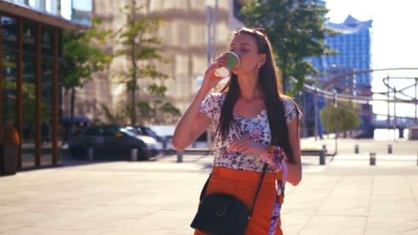 En ung kvinna väntar på någon i staden och dricka en kaffe att gå — Stockvideo
