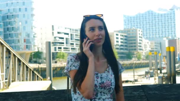 Eine junge Frau, die auf einem Smartphone spricht und lacht — Stockvideo