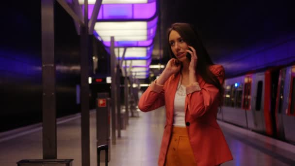 In attesa della metropolitana - una giovane donna d'affari che parla su smartphone e ride — Video Stock