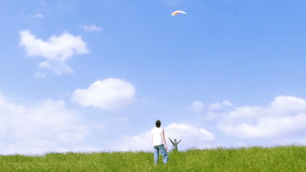 Une famille volant cerf-volant dans le ciel bleu avec quelques nuages . — Video