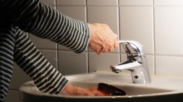 Nalévání vody do skleničky v koupelové místnosti. — Stock video