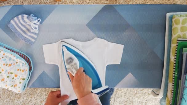 Motherhood. Female hands ironing clothes with iron on ironing board — Stock Video
