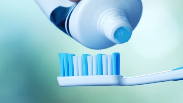 Saúde Dental - Espremendo pasta de dentes azul de um tubo em uma escova de dentes . — Vídeo de Stock