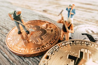 Değerli madeni para ahşap arka plan üzerinde kazma Bitcoin madenciliği minyatür insanlar