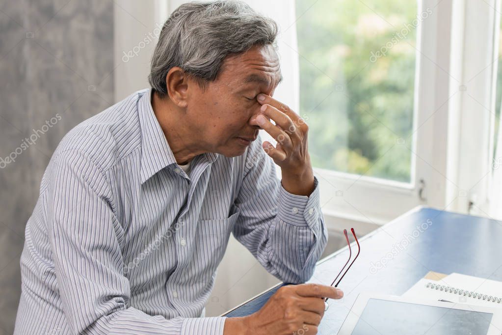 Asian elderly stress tired and holding his nose suffer sinus pain fatigue from hard work.
