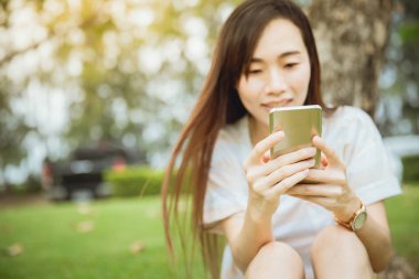 Asya teen zevk akıllı telefon bağlantısı yaşam tarzı açık yeşil park kullanarak.