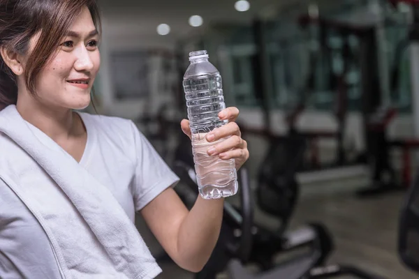 healthy asian woman looking at drink water with sport club background