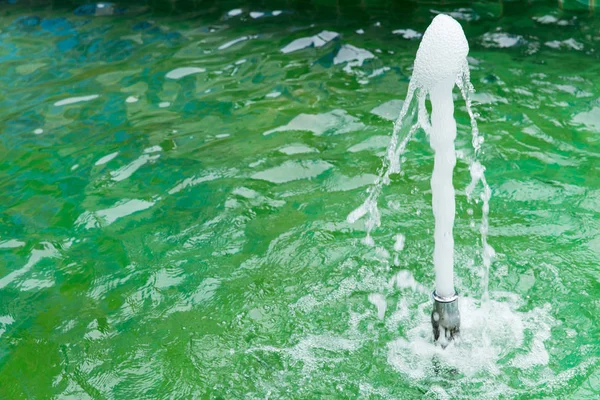 green water fountain from water pump jet at building facade