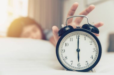 Pazartesi sabah saat çalar saat yüzük yatakta kız elini uyandırmak için tembel