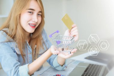 Genç Asyalı kız ofis kavramında online alışveriş için kredi kartı kullanarak mutlu.