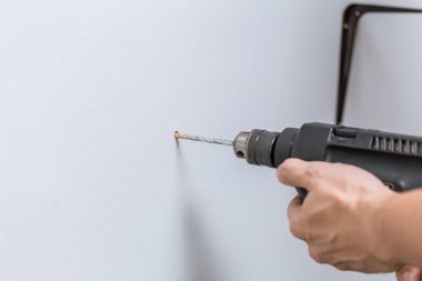 ev yenileme closeup el kayan raflar yüklemek için duvardaki bit delik delme için matkap kullanarak