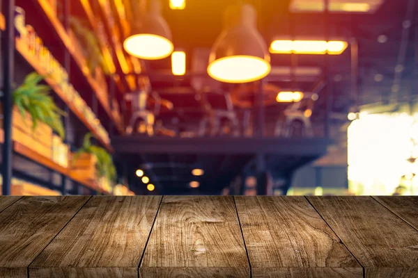 wooden table foreground with blurred cafe restaurant lights background for montage products.