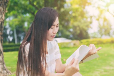 Asya ince teen sakin okuma ağacın altında yeşil park