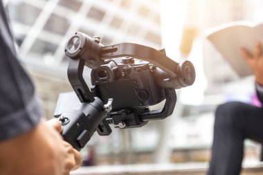 Dengeleyici video sahnesi için dslr kamera anti-sallama aracı kullanan motorlu gimbal ve videograf.