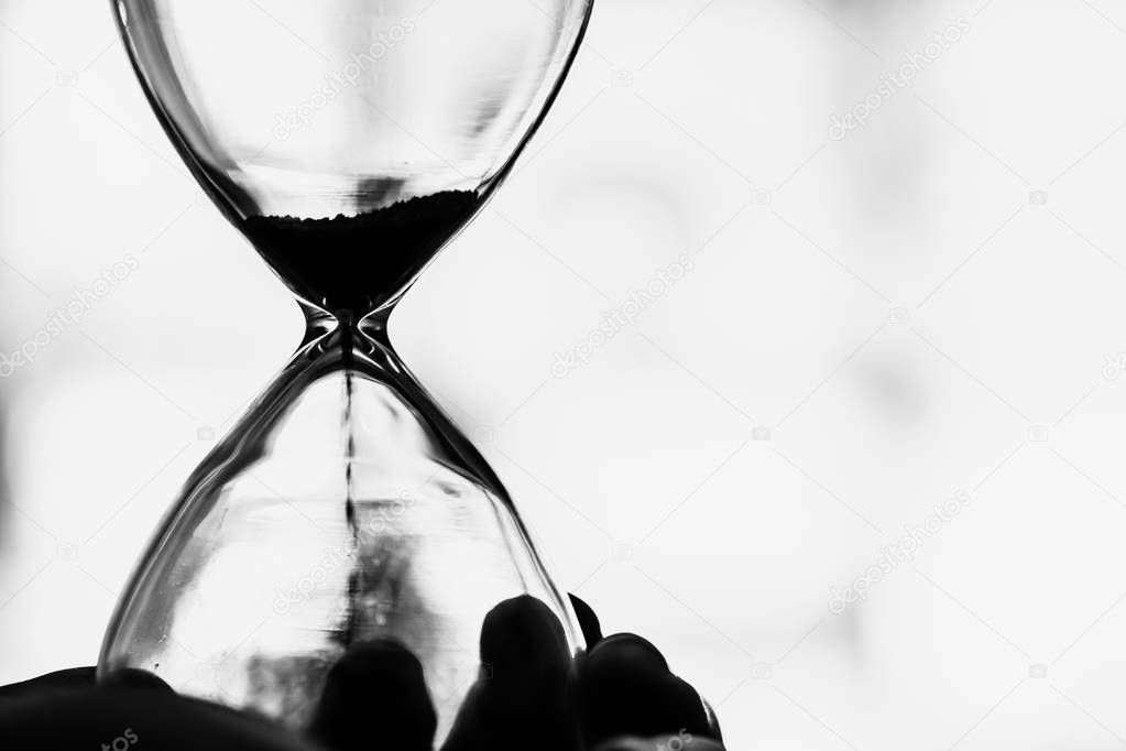Working times countdown concept. Closeup Hourglass black and white vintage tone.