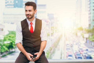 latin Latin asıllı işadamı gülümseme şehir bulanıklık arka plan el tutun smartphone ile oturan.