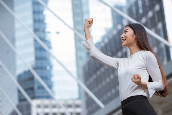 women rise her hand for business winner success concept with office building background.