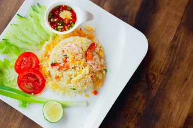 Tay tarzı Karides Kızarmış Pilav Tarifi Üst görünüm beyaz çanak sebze dekorasyonu ile ahşap masada servis