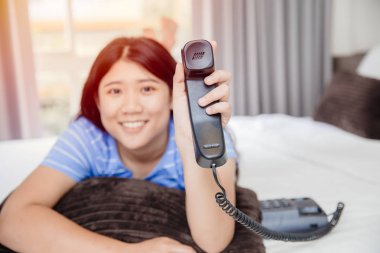 Sabit telefonu olan Asyalı bir genç kız. Mutlu bir gülümseme. Müşteri desteği kavramı etkileyici..