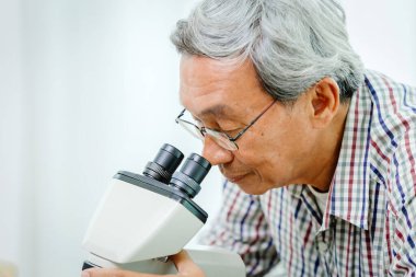 Hastane laboratuarında mikroskoba bakan Asyalı bir doktor var.
