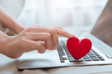 Flört etmek için dizüstü bilgisayarda kırmızı kalbe dokunmak ya da Coronavirus salgını sırasında sevgili bulmak için internetten mesajlaşmak.