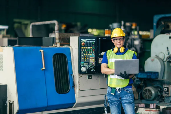 Asian engineer working programming the machine in factory with laptop computer to setup program process, Portrait looking camera of industry worker.