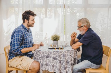 Akıllı yaşlılar evde satranç oynuyor. Beyni sağlıklı kalmak için daha genç erkeklerle.