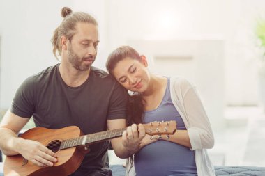 Hamile eşi olan koca evde kalır. Bebek için gitar çalar, öpüşür ve birlikte sevgi gösterirler.
