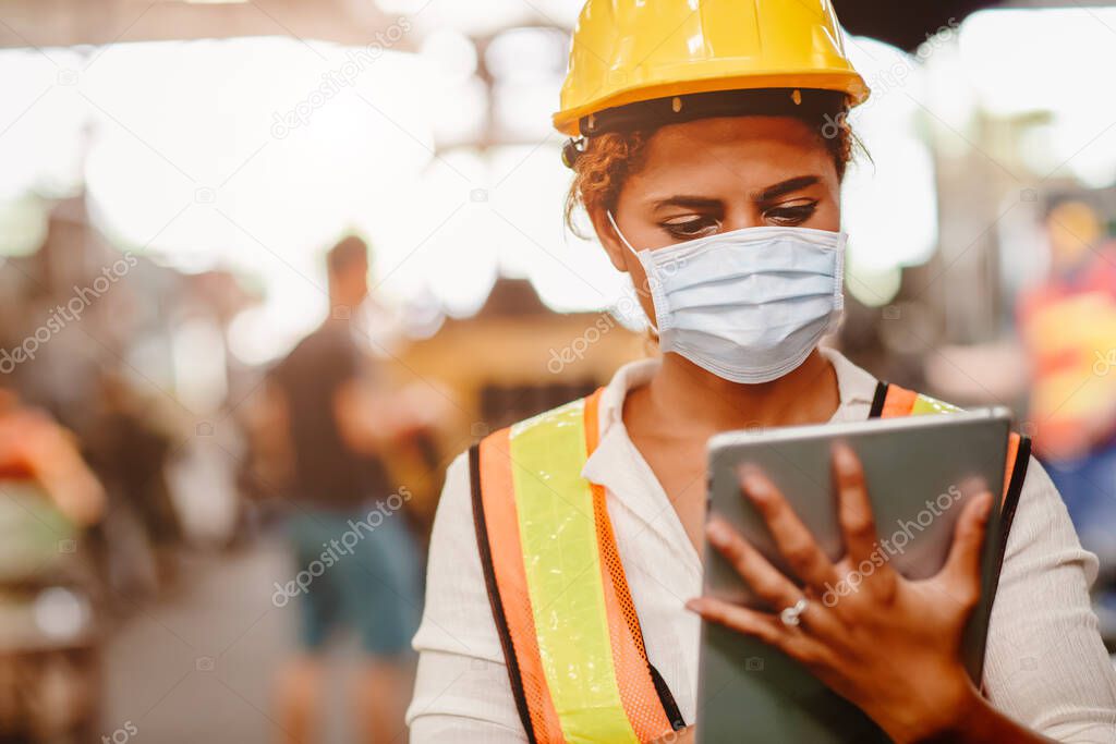 African American black women teen worker wearing face shield or disposable face mask during working in factory for prevent spreading of Coronavirus(Covid-19) and air dust pollution for labor healthy.