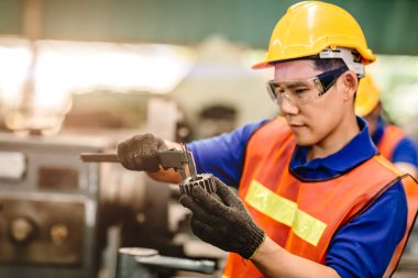Fabrikadaki servis makinesinin doğruluk hassasiyeti kalite kontrolü için Vernier Caliper kullanan Asyalı mühendis..