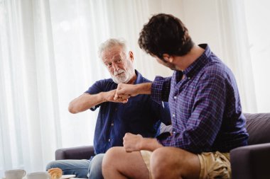 Bir adam, büyükbabasıyla, büyükbabasıyla ya da yaşlı bir adamla el sıkışır. Oğluyla el ele tutuşur..