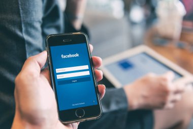 Cep telefonunda sosyal ağ güvenliği için tablet arka planını kullanan insanların olduğu Facebook Uygulama giriş sayfası., 20 Temmuz 2019, Bangkok, THAILAND.