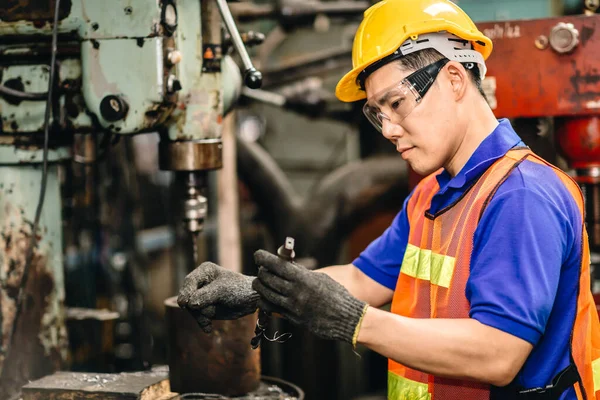 重工業工場の金属穴あけ加工機のドリルビットをチェックして交換するエンジニア労働者 — ストック写真