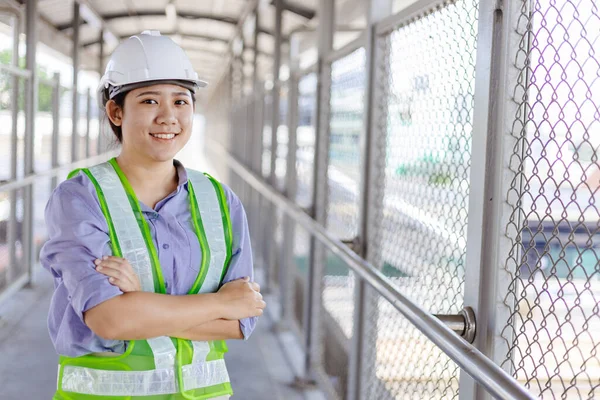 年轻的亚洲商业工程师或技术检查员 戴着安全帽 手挽手站在建筑工地上 面带微笑地看着相机 — 图库照片
