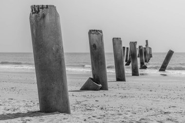 Sahildeki terk edilmiş beton kutup, siyah beyaz sanat fotoğrafçılığı.