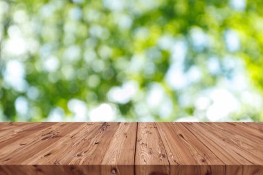 Çevre ürünleri montaj arka planı için ahşap masa alanı olan bulanık yeşil ağaç yaprağı bahçesi