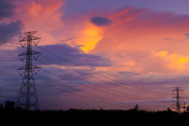 Elektrik hattı, yüksek voltajlı güç iletim kulesi alacakaranlık şafağına karşı şehir merkezine.