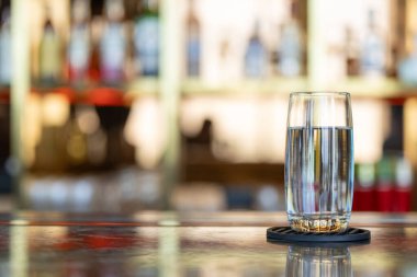 Bir bardak içme suyu, berrak bardaktaki temiz su lüks bar arka planında metinler için yer var.