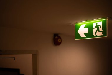 Ok yönünden çıkış yolu, kaçış kılavuzu yeşil ışık çıkış işareti tavan koridorundaki karanlık oda tesisinde acil çıkış işareti.