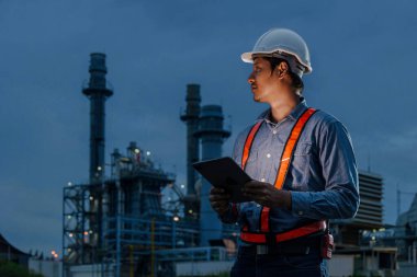 Gece vardiyası mühendisi, petrol rafinerisi, erkek işçi, petrol endüstrisinde sıkı çalışma karanlık arka plan..