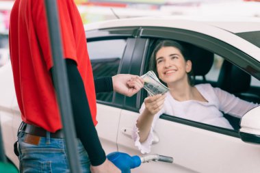 Benzin istasyonu çalışanı, araç sahibi Petrol şirketinden akaryakıt faturası ödemesi için nakit para alıyor.