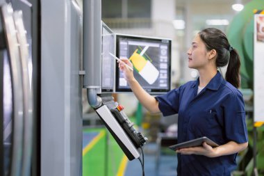 Modern çelik endüstrisi fabrikasında CNC torna makinesinde çalışan genç mühendis kadınlar.